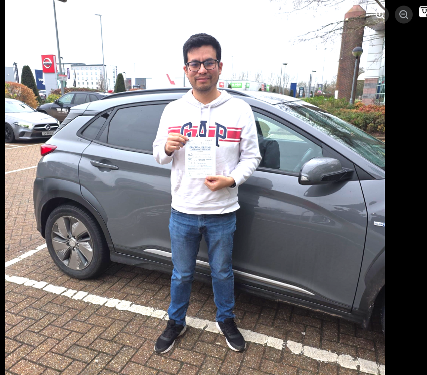 Student holding a pass certificate beside the lesson car