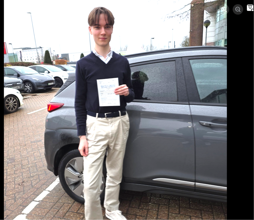 Student holding a pass certificate beside the lesson car