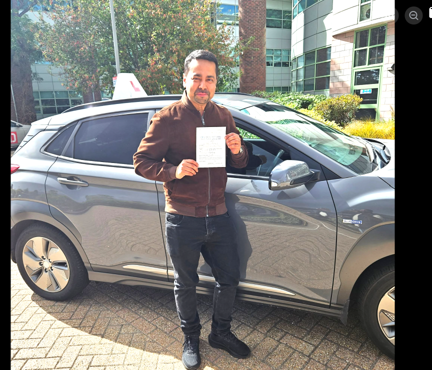 Student holding a driving test pass certificate beside the lesson car