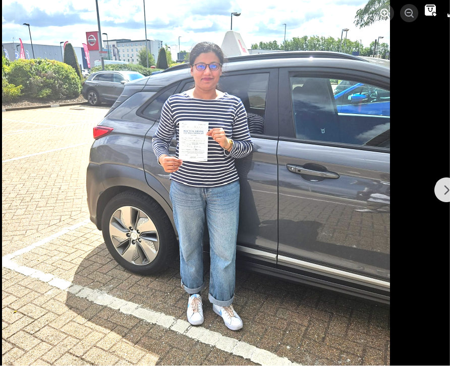 Student holding a pass certificate beside the lesson car