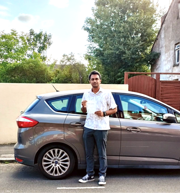 Student holding a pass certificate beside the lesson car