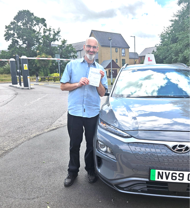 Student holding a pass certificate beside the lesson car