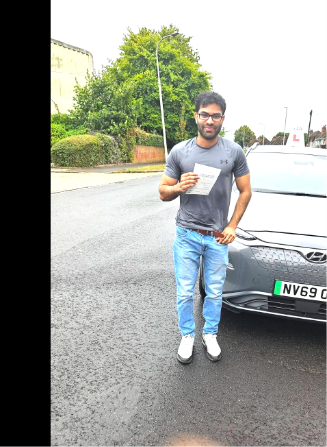 Student holding a pass certificate beside the lesson car